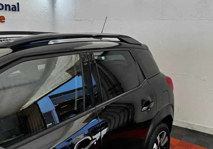 Vue latérale arrière droite d'un Citroën C3 Aircross noir avec barres de toit et jantes alliage visibles.