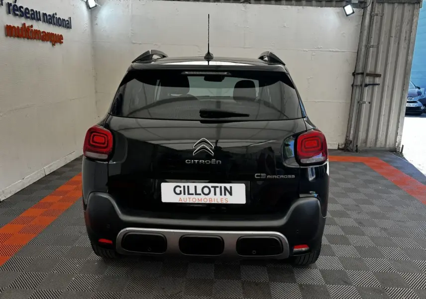 Vue arrière d'un Citroën C3 Aircross noir 2020 avec feux arrière carrés et pare-chocs noir mat, en intérieur showroom.