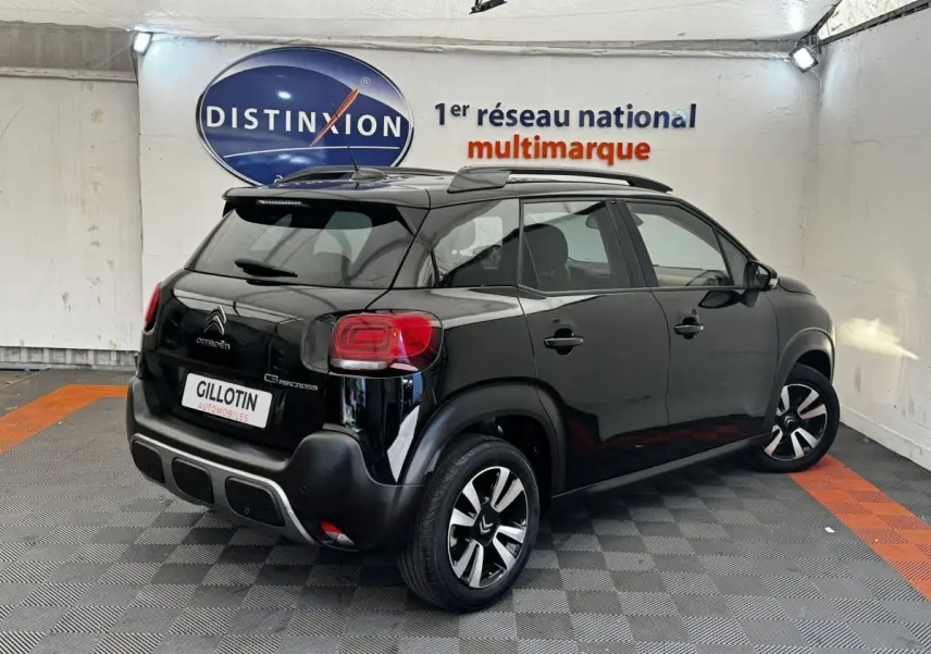 Vue 3/4 arrière droite d'un Citroën C3 Aircross noir avec barres de toit et jantes distinctives en concession.