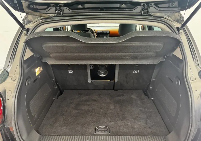 Coffre ouvert vu de l'arrière d'une Citroën C3 Aircross noire, montrant l'espace de chargement et la tablette de séparation.