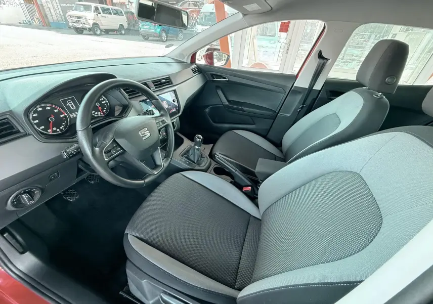 Vue intérieure côté conducteur de la SEAT Ibiza 2020, montrant sièges tissu gris noir et volant cuir multifonction.