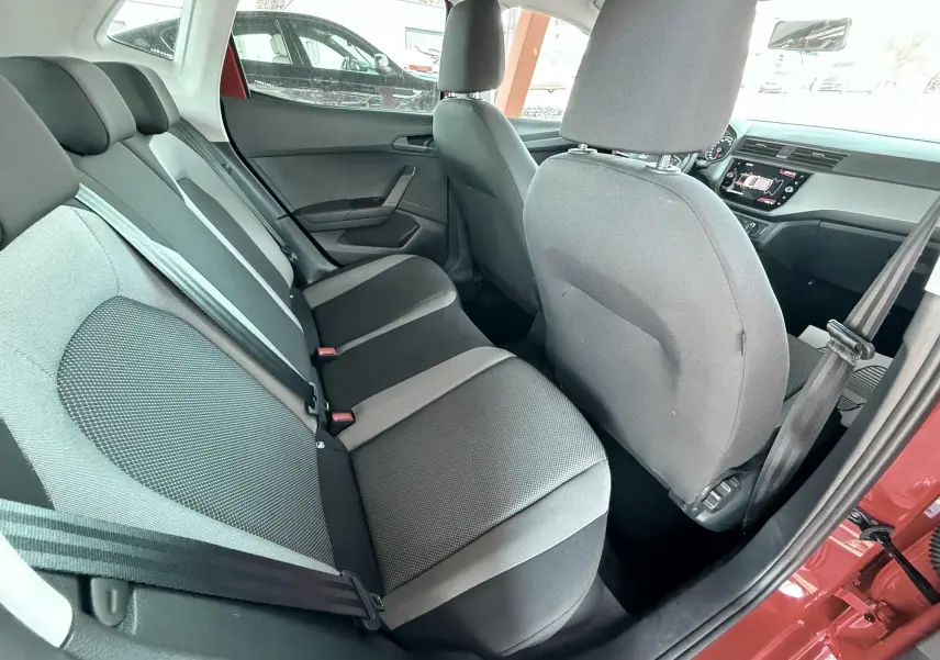 Vue intérieure côté arrière droit montrant les sièges tissu gris et noir d'une SEAT Ibiza rouge passion 5 portes.