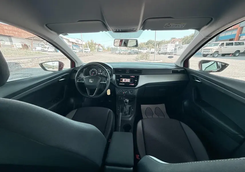 Vue intérieure avant de la SEAT Ibiza 1.0 rouge passion, montrant le tableau de bord et la console centrale avec boîte manuelle.