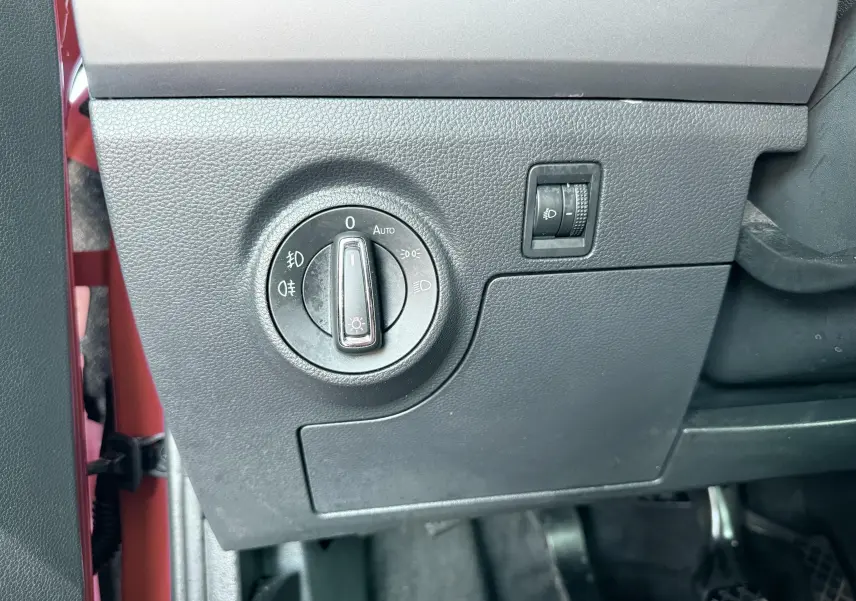 Gros plan sur le bouton de commande des phares à gauche du volant dans une SEAT Ibiza rouge passion 2020.