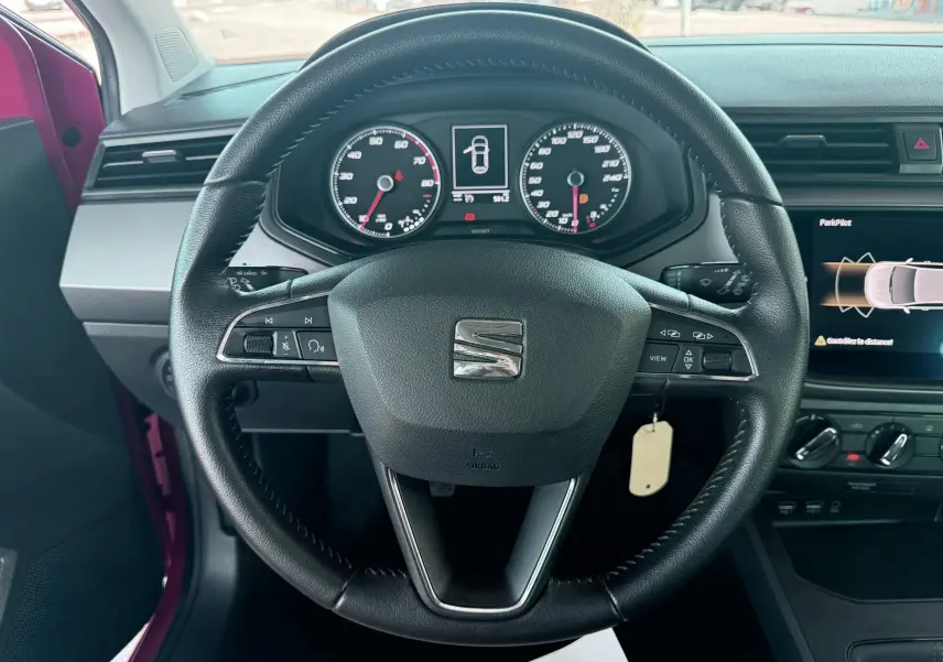 Vue rapprochée du volant en cuir noir d'une SEAT Ibiza 2020 avec tableau de bord et écran multimédia allumé.