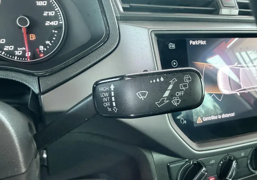 Gros plan sur la commande d’essuie-glace à gauche du volant dans l’habitacle gris noir d’une SEAT Ibiza rouge.