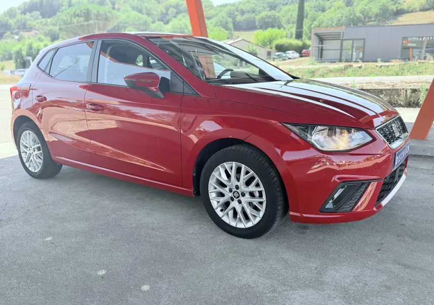SEAT Ibiza rouge passion vue 3/4 avant droit, mettant en valeur ses jantes alliage et lignes dynamiques.