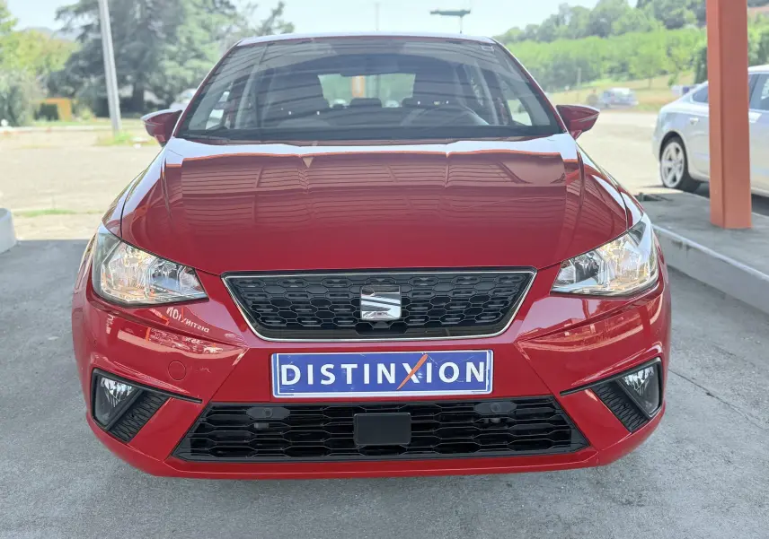 Vue avant d'une SEAT Ibiza rouge passion métal avec calandre noire et plaque d'immatriculation Distinxion.