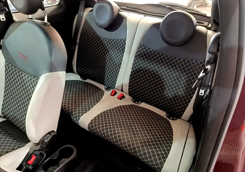 Vue intérieure côté droit des sièges arrière et avant en tissu noir à motifs blancs de la FIAT 500 rouge de 2021.