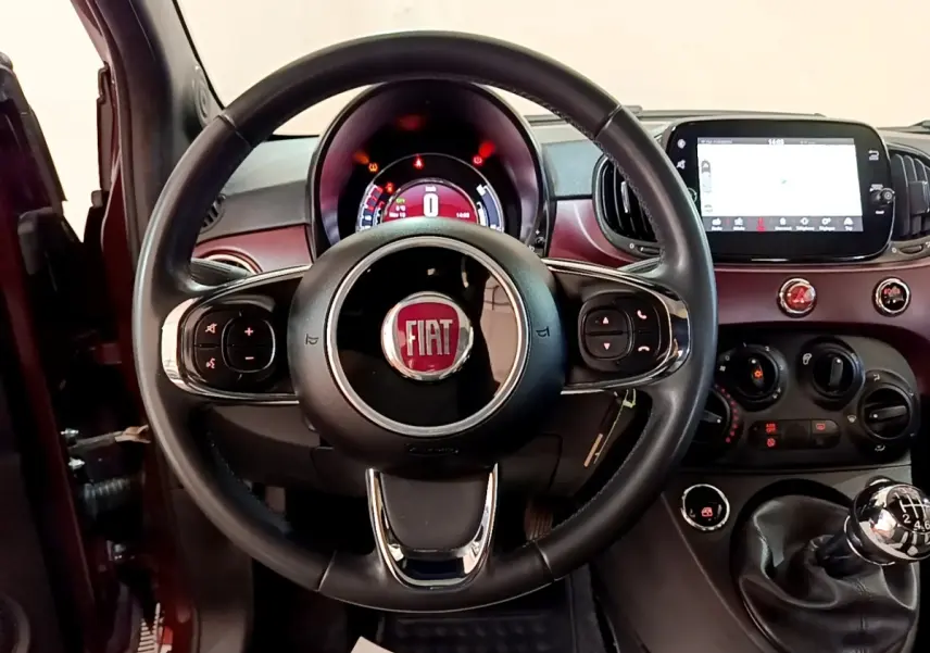 Vue intérieure centrée sur le volant cuir et tableau de bord rouge de la Fiat 500 1.0 70ch BSG Star 2021.