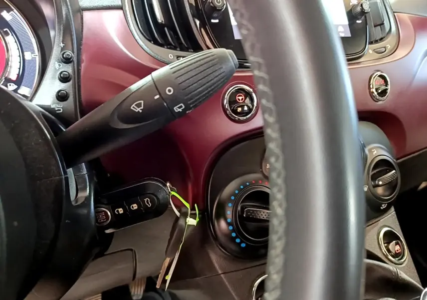 Vue rapprochée du tableau de bord rouge de la Fiat 500 1.0 70ch BSG Star, volant cuir et commandes visibles.