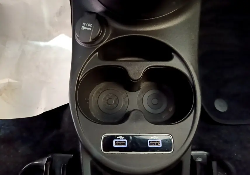 Vue rapprochée de la console centrale noire avec porte-gobelets et deux ports USB de la Fiat 500 rouge 2021.