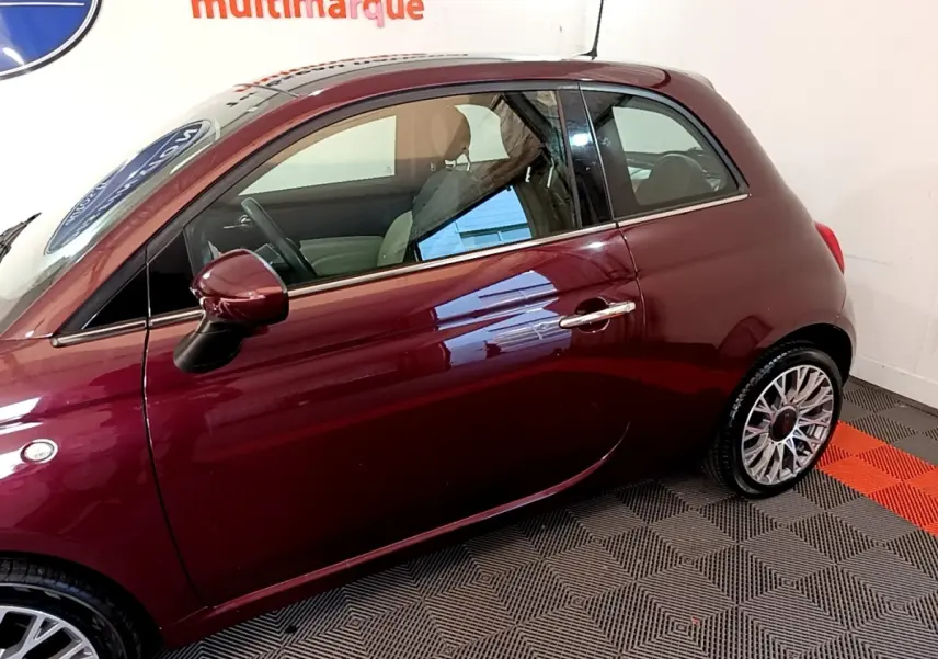 Profil côté gauche d'une FIAT 500 rouge bordeaux 2021 avec jantes alliage et rétroviseurs assortis.