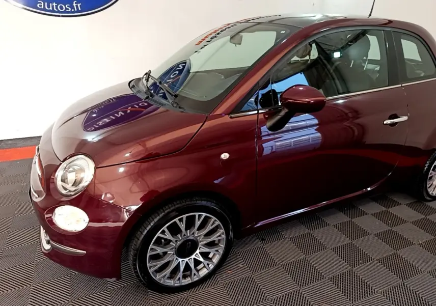Fiat 500 rouge vue 3/4 avant droit, mettant en valeur ses phares ronds et jantes alliage multibranches.