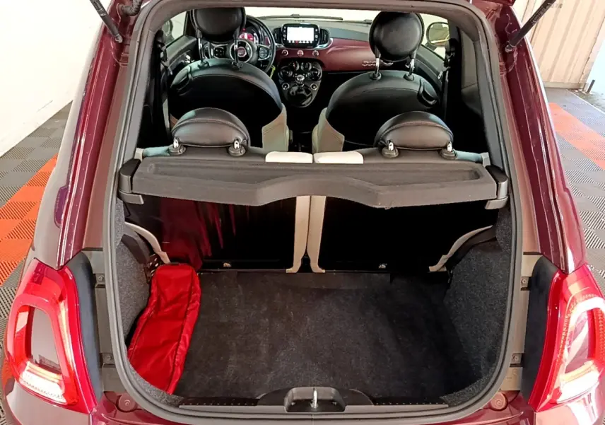 Vue arrière du coffre ouvert d'une FIAT 500 rouge 2021, montrant l'intérieur et les sièges noirs avec détails clairs.