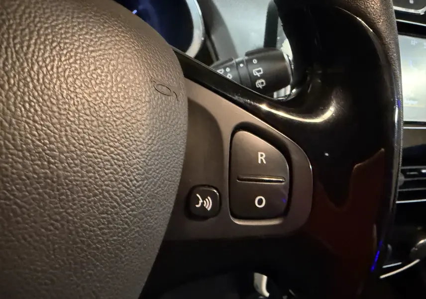 Gros plan sur les commandes du volant noir de la Renault Clio Estate IV rouge, version Limited essence 2015.