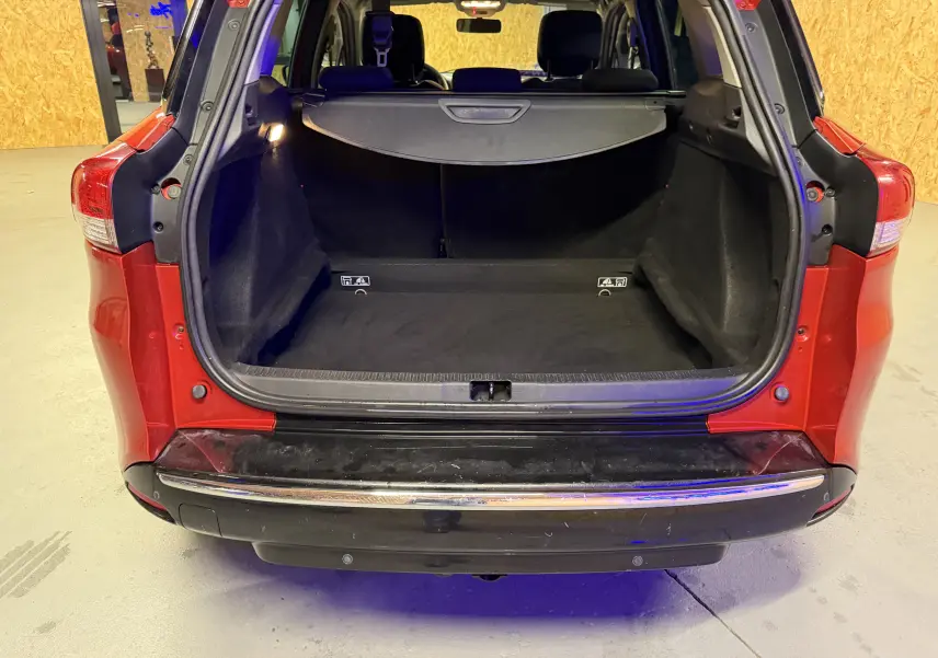 Coffre ouvert vu de l'arrière d'une Renault Clio Estate IV rouge, montrant l'espace de chargement vide et la plage arrière.