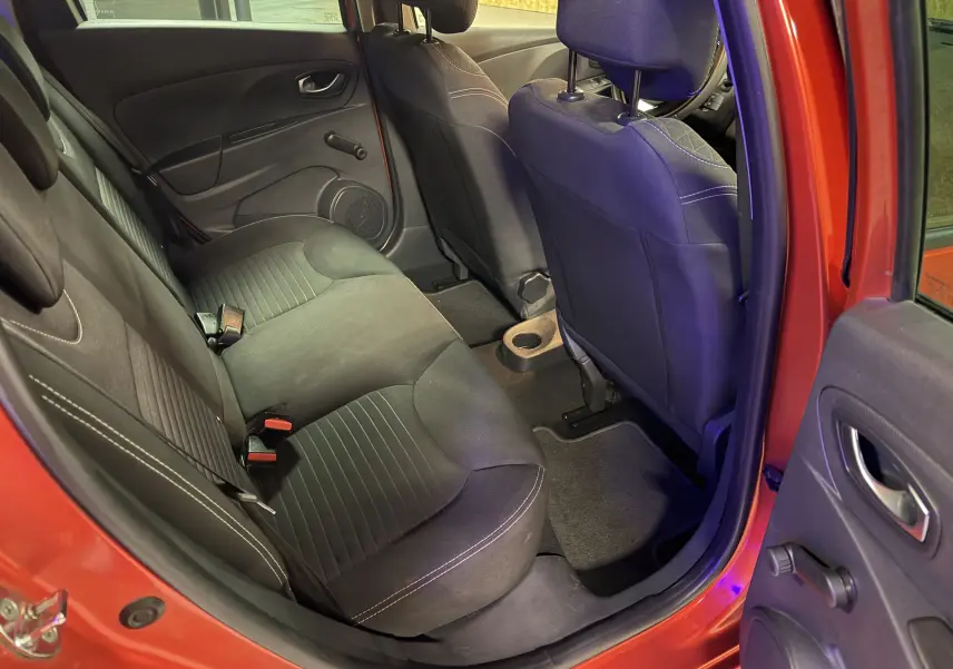 Intérieur arrière de la Renault Clio Estate IV rouge, vue côté gauche avec sièges noirs et porte ouverte.