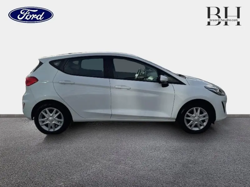 Vue de profil côté gauche d'une Ford Fiesta blanche Glacier 5 portes, avec enjoliveurs et poignées ton carrosserie.