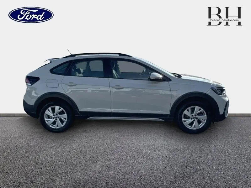 Vue de profil côté gauche d'un Volkswagen Taigo blanc pur 2024 avec barres de toit et jantes alliage.