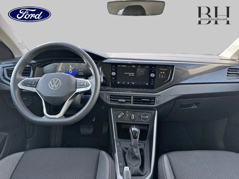 Intérieur avant du Volkswagen Taigo blanc, vue centrée sur le volant multifonction et l’écran tactile du tableau de bord.