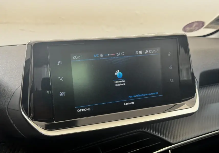 Écran tactile central noir affichant la connexion Bluetooth dans l’habitacle d’une Peugeot 208 blanche.