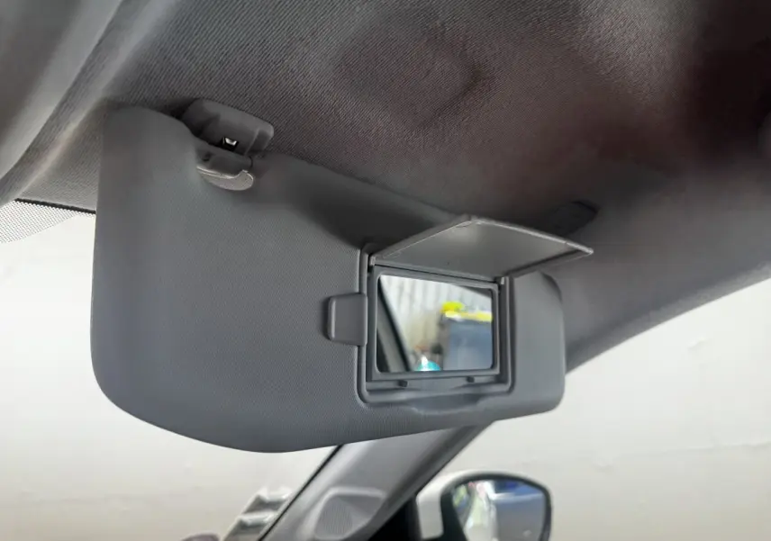 Détail du pare-soleil côté conducteur avec miroir de courtoisie ouvert dans une Peugeot 208 blanche.