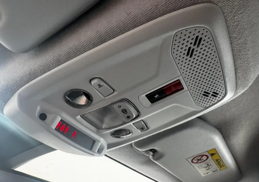 Vue intérieure du plafonnier gris clair de la Peugeot 208 blanc, avec commandes d’éclairage et bouton SOS rouge.