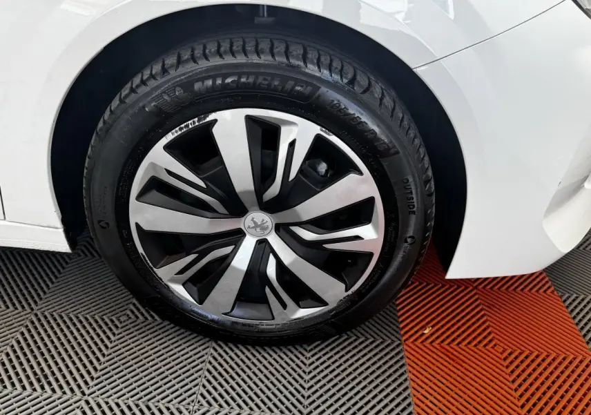 Gros plan sur la roue avant gauche blanche d'une Peugeot 208 PureTech 100 S&S Active Business avec jante spécifique.
