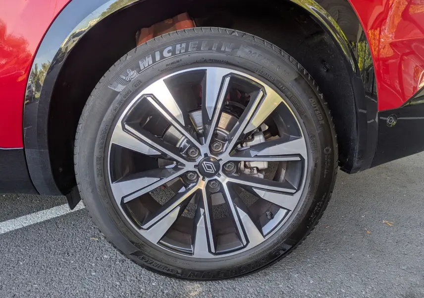 Gros plan sur la roue avant droite du Renault Austral rouge Flamme, avec jante alliage bicolore et pneu Michelin.