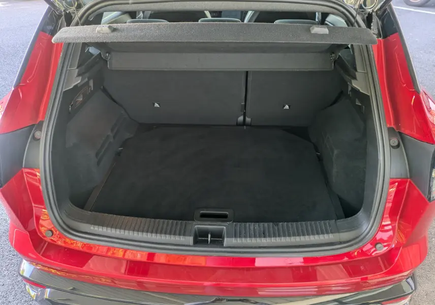 Coffre ouvert vu de l'arrière d'un Renault Austral 2025 Rouge Flamme, montrant un espace de chargement propre et spacieux.
