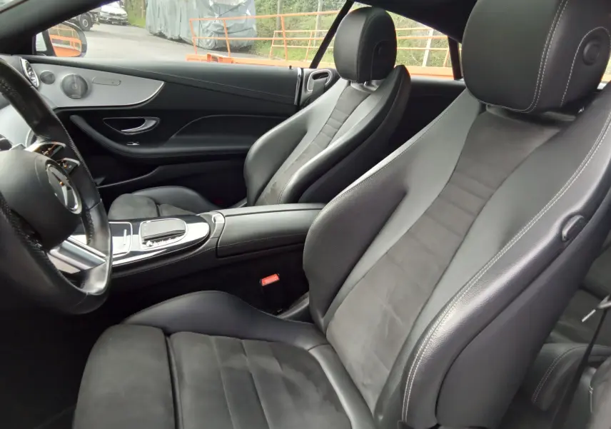 Intérieur noir en cuir de la Mercedes Classe E Coupé 220D AMG Line, vue côté conducteur avec volant et console centrale.