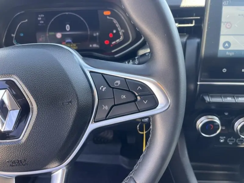 Gros plan sur le volant multifonction noir de la Renault Clio 1.6 E-Tech 140ch Business avec tableau de bord numérique et écran tactile.