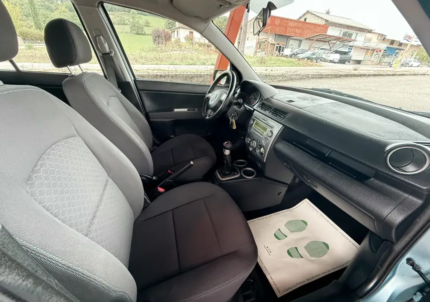Intérieur noir et gris de la Mazda2 2004, vue côté conducteur montrant sièges, volant et tableau de bord.