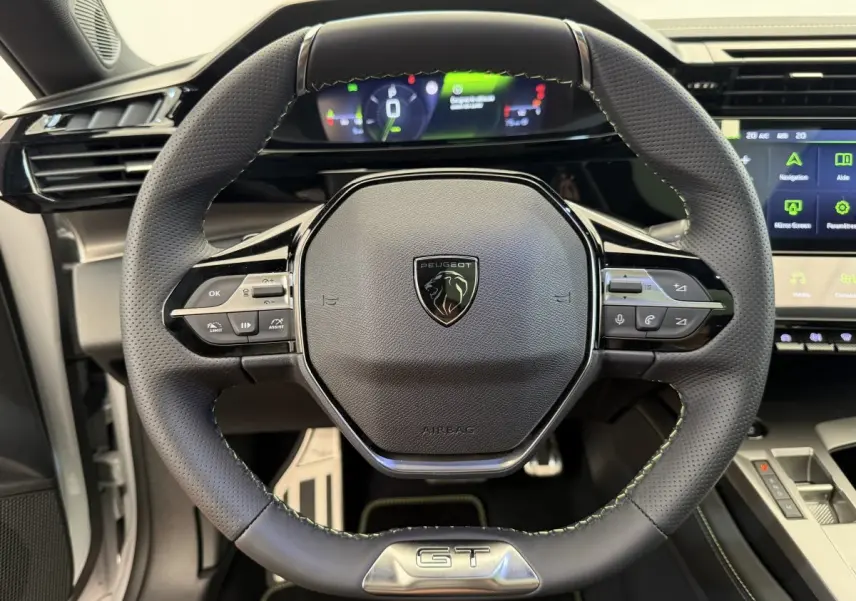Volant cuir noir avec logo Peugeot et badge GT, tableau de bord numérique et écran tactile de la Peugeot 308 Hybrid 2024.