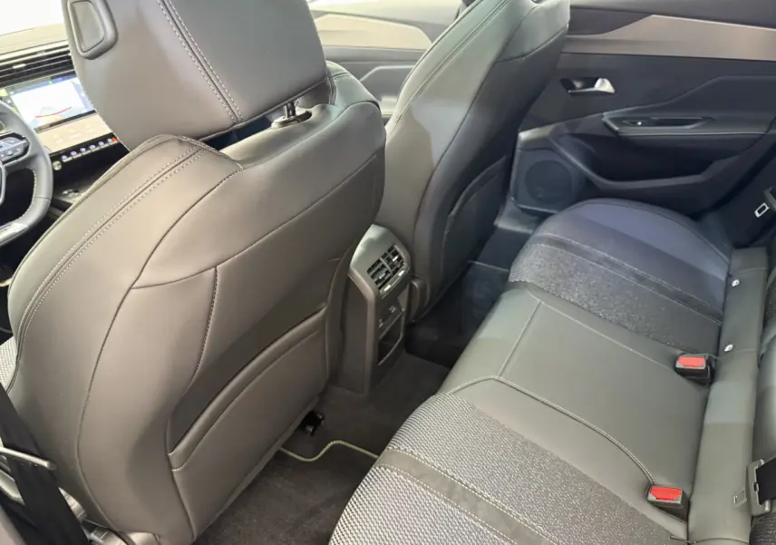 Vue intérieure arrière côté droit du Peugeot 308 Hybrid 136 e-DCS6 GT 2024 avec sièges noirs en cuir et tissu.