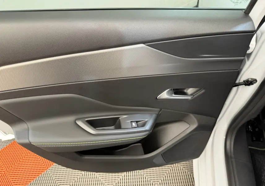 Porte intérieure côté avant gauche de la Peugeot 308 Hybrid blanche, avec garniture noire et surpiqûres vertes.