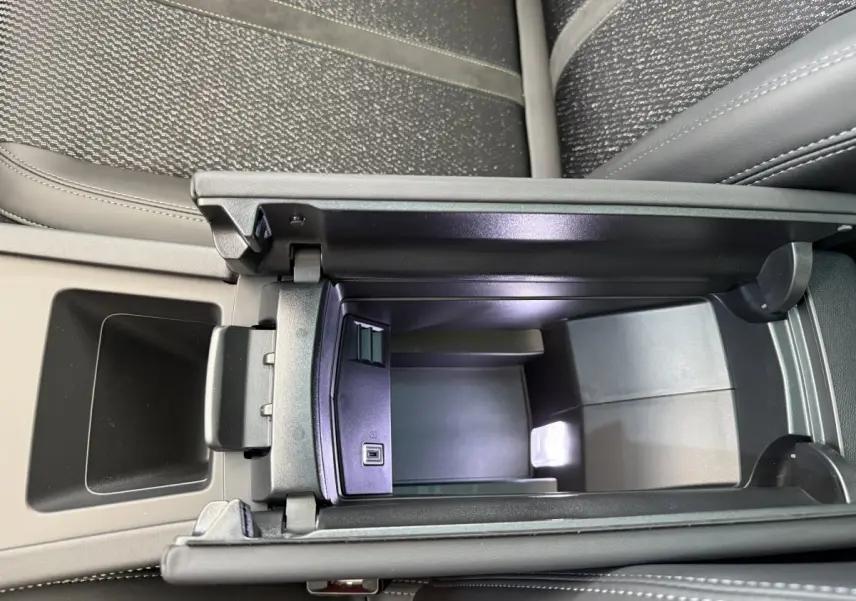 Vue plongeante sur la console centrale noire ouverte du Peugeot 308 Hybrid 136 e-DCS6 GT avec sellerie grise.