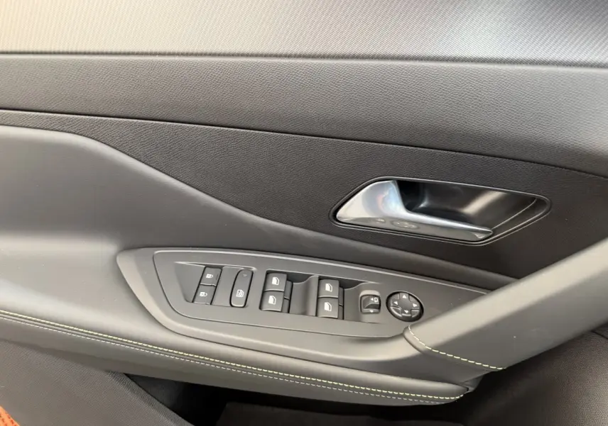 Détail de la porte côté gauche intérieure d'une Peugeot 308 Hybrid blanche, avec commandes vitres et poignée chromée.
