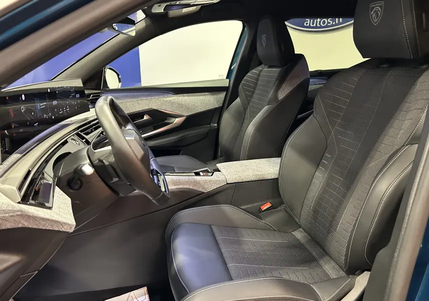 Intérieur du Peugeot 5008 Hybrid 2025 vu côté conducteur, sièges cuir noir avec surpiqûres blanches et tableau de bord moderne.