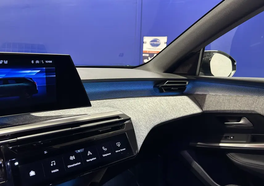 Intérieur avant droit du Peugeot 5008 III Hybrid 145 GT avec tableau de bord texturé gris et éclairage d'ambiance bleu.