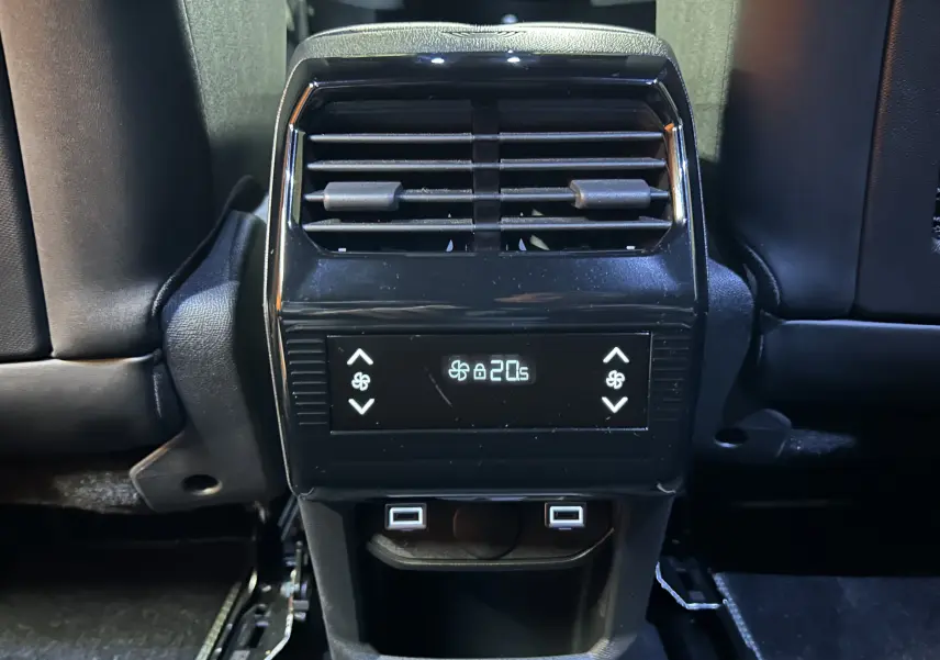 Vue rapprochée de la console arrière noire du Peugeot 5008 bleu Obsession, avec commandes climatisation et ports USB visibles.