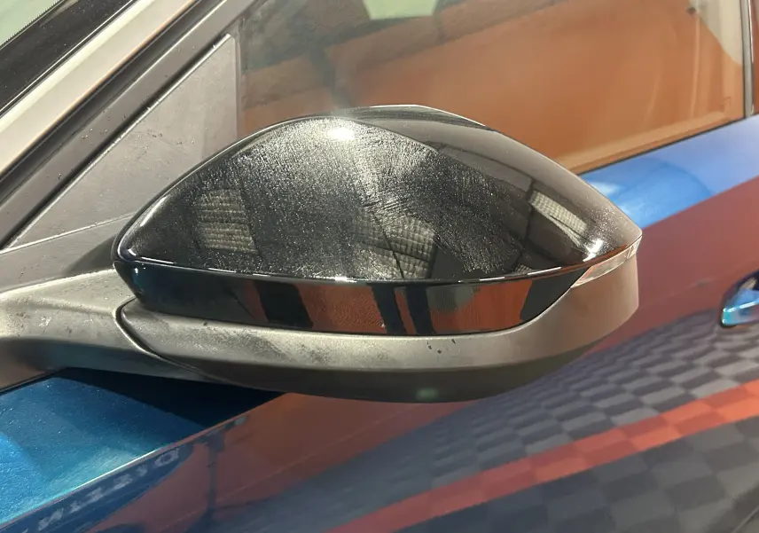 Rétroviseur noir brillant côté gauche sur Peugeot 5008 bleu obsession, vue rapprochée en extérieur.