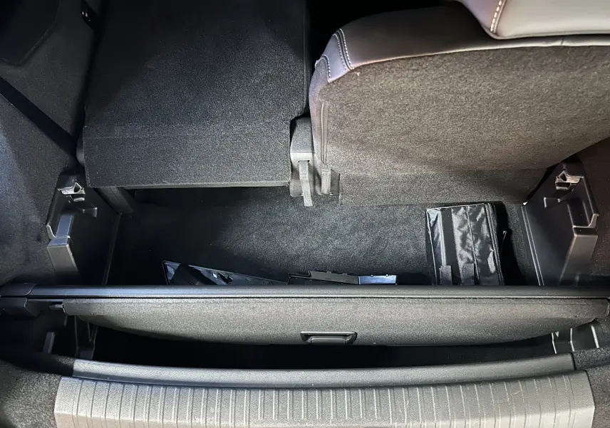 Vue plongeante sur le coffre arrière du Peugeot 5008 III Hybrid 145 GT en bleu Obsession, montrant le plancher relevé et rangement.