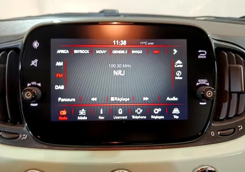 Écran tactile central affichant la radio NRJ dans l'habitacle beige clair d'une Fiat 500 Lounge 2019.