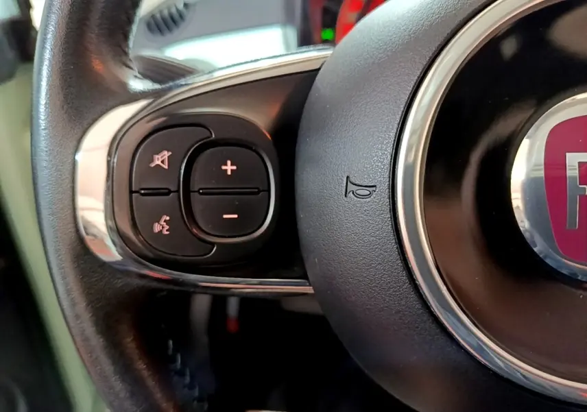Gros plan sur le volant cuir multifonctions de la FIAT 500 Lounge 2019, boutons de contrôle audio visibles.