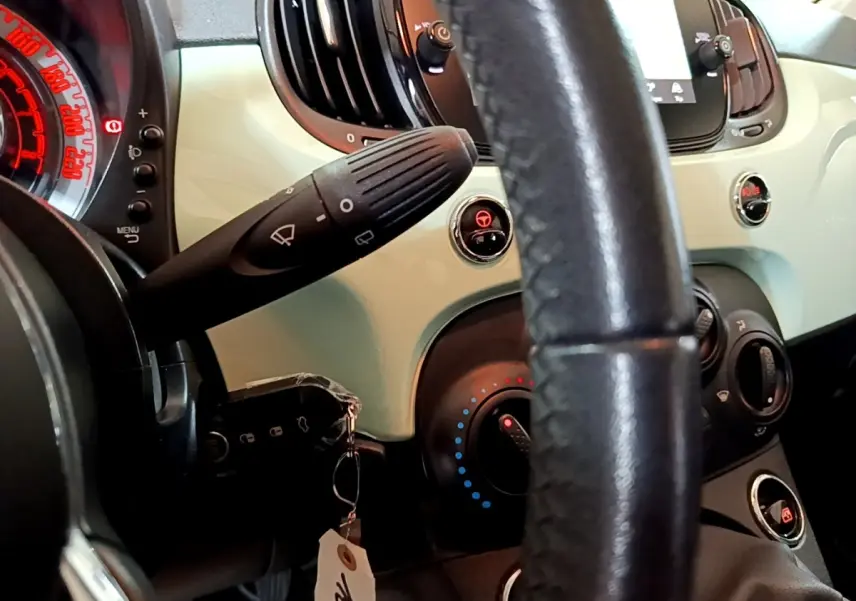 Gros plan sur le tableau de bord vert clair et le volant cuir noir de la Fiat 500 2019 version Lounge.