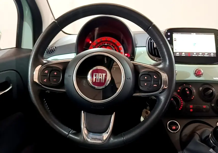 Vue intérieure centrée sur le volant cuir noir de la Fiat 500 Lounge vert avec tableau de bord et écran tactile.