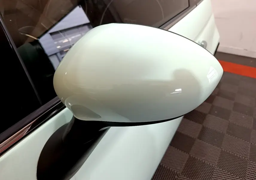 Gros plan sur le rétroviseur côté droit vert clair d'une FIAT 500 Lounge 2019, avec carrosserie et vitre partiellement visibles.