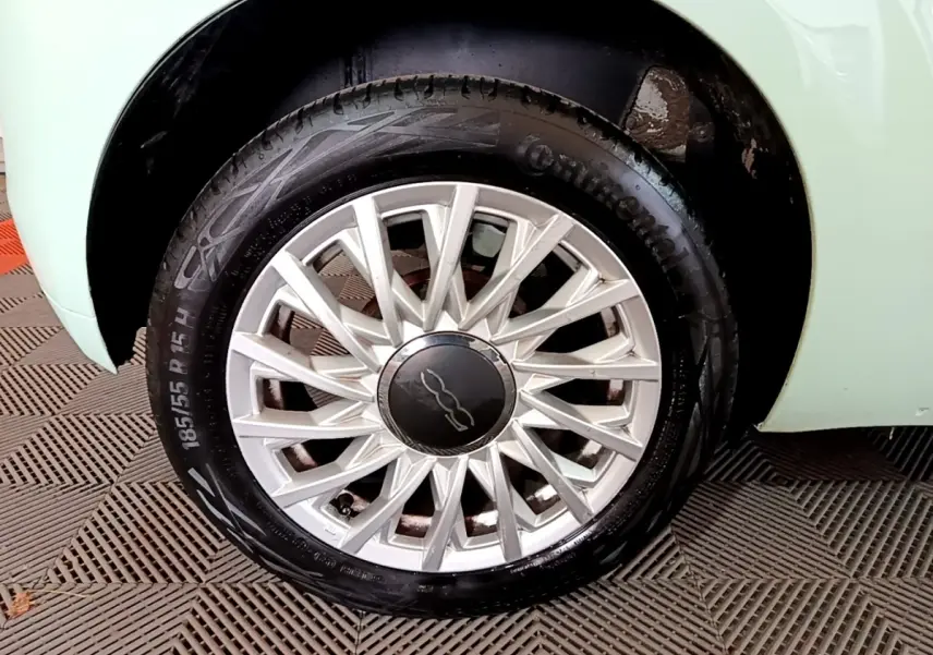 Gros plan sur la roue avant gauche d'une FIAT 500 verte, mettant en valeur la jante alu à rayons fins et le pneu Continental.